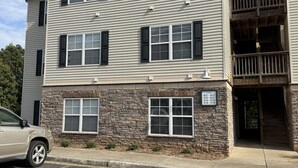 A multi-story building with a stone facade, multiple windows, and a parking lot. - Lake Hartwell/Clemson University 3 bd/2 bath condo (Anderson)