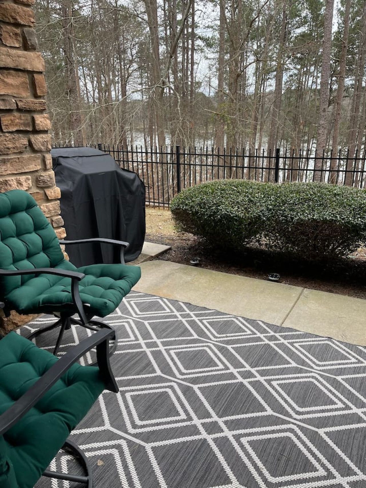 Une terrasse extérieure avec un mur en pierre, un barbecue abrité et une haie.