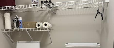 A laundry area with a washing machine, dryer, and shelves with laundry supplies.