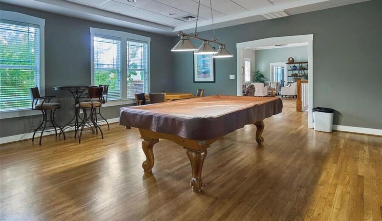 A spacious room with a pool table, chairs, and a dining area.