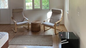 A spacious room with a sloped ceiling, two large windows, a bed, two chairs, a small round table, and a black cabinet. - Yedi (7) Boutique Hotel (Kemer)