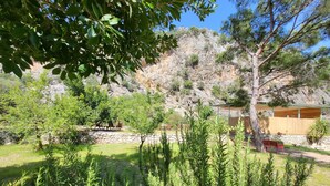 A rustic outdoor area with a stone wall, wooden benches, and a wooden structure with a roof. - Yedi (7) Boutique Hotel (Kemer)