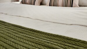 A neatly made bed with striped pillows, a white headboard, and a green throw blanket. - Yedi (7) Boutique Hotel (Kemer)