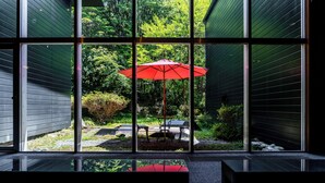 A modern interior with large windows, a red umbrella, and outdoor seating. - YuYu Hakone - Private Open Air Onsen Usage Guaranteed (Hakone)