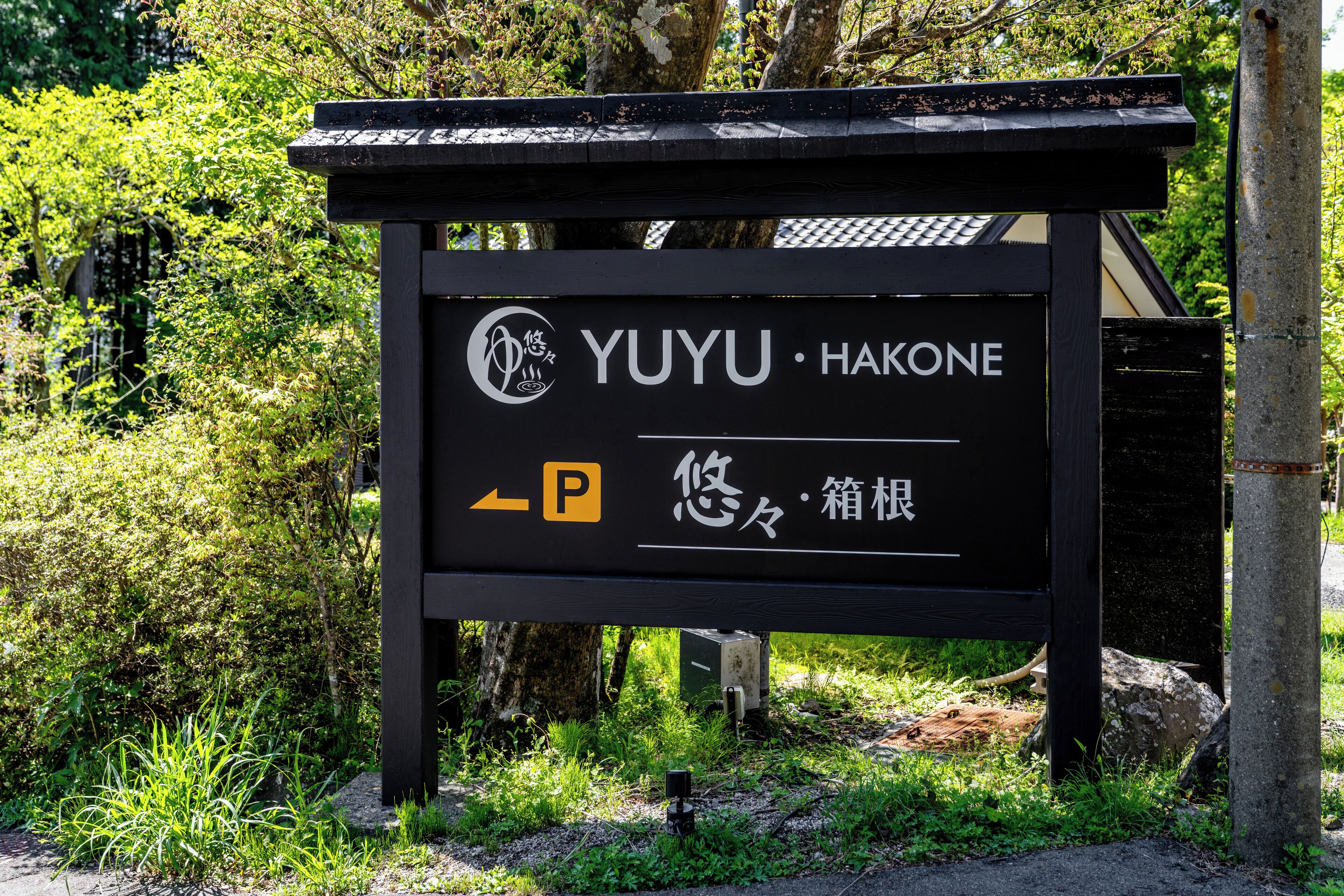 A black sign with "YUYU HAKONE" and a parking symbol.