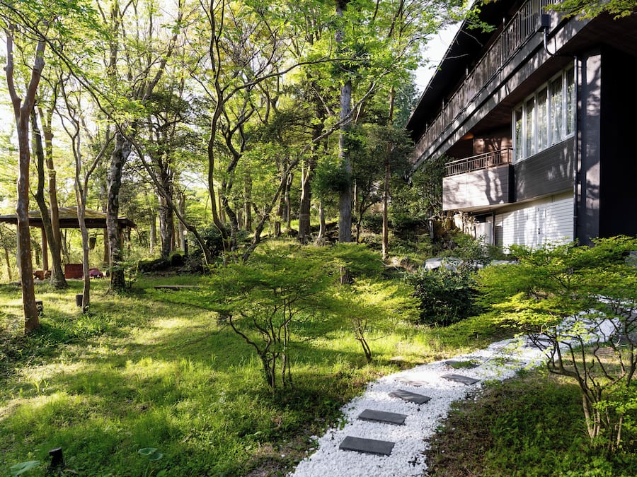 A traditional Japanese-style building with a wooden deck and a stone pathway leading to the entrance.