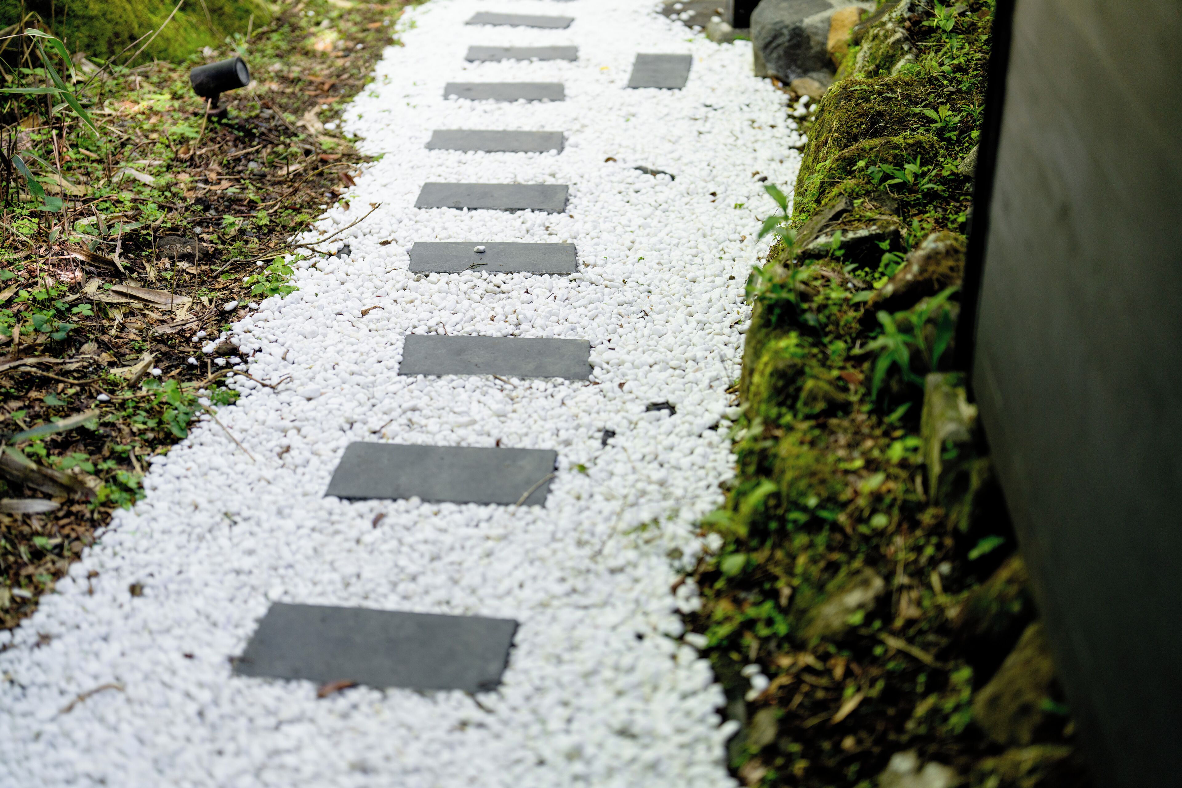 Un camino con guijarros blancos y losas de piedra rectangulares.