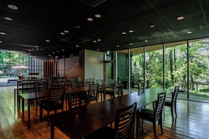 Un amplio comedor interior con mesas y sillas grandes, un techo moderno con iluminación empotrada y ventanas grandes que ofrecen vistas al exterior.