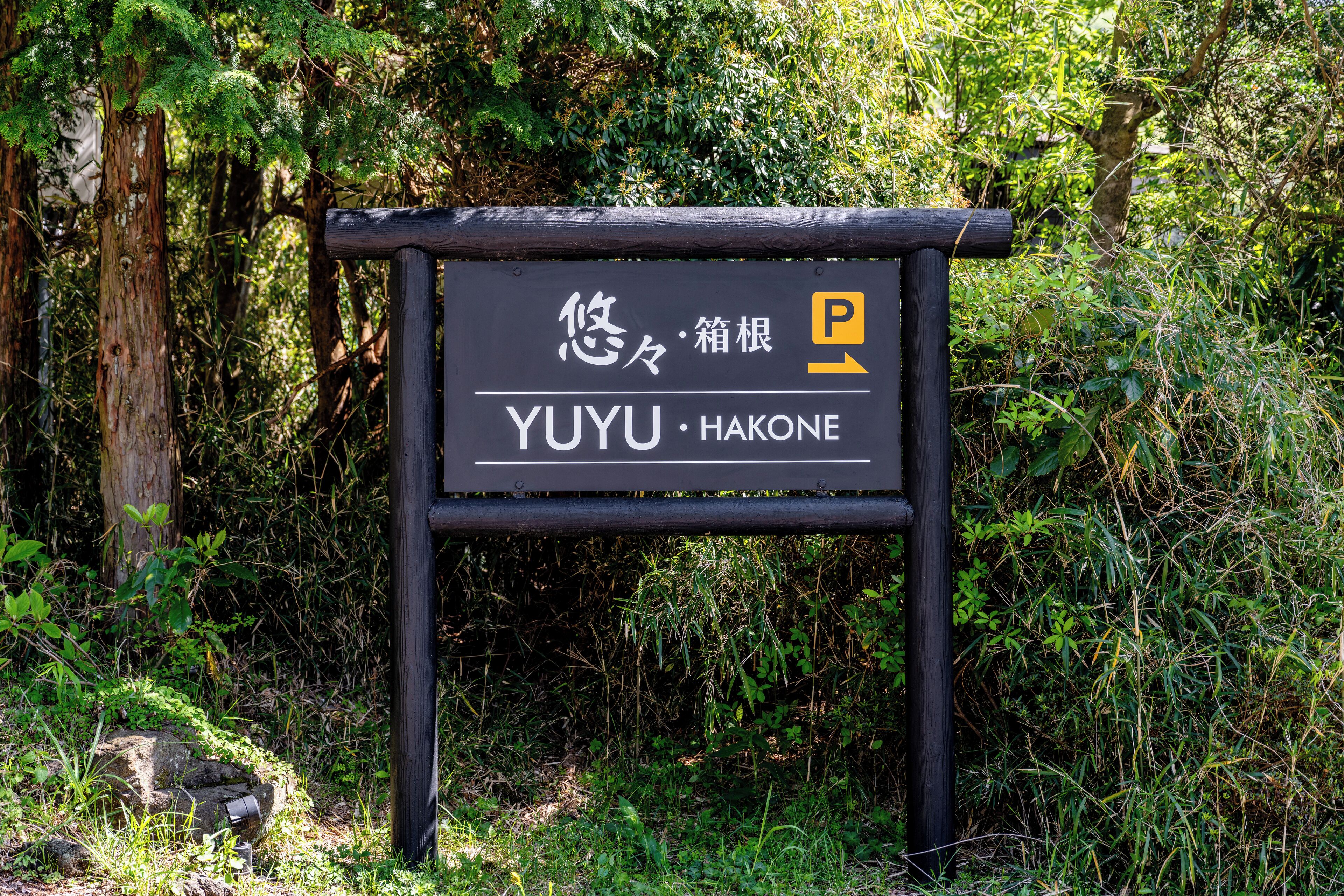 Ein Schild mit japanischen Schriftzeichen und dem Schriftzug 'YUYU HAKONE', das einen Ort angibt.