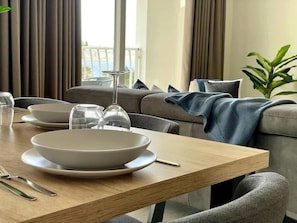 A dining area with a table set for two, a sofa, and a view of the outdoors.