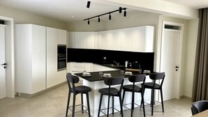 Una cocina moderna con armarios blancos, una isla de encimera negra y cuatro taburetes de bar.