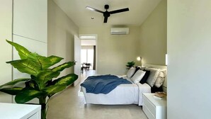 Un dormitorio con cama, mesitas de noche, ventilador de techo, aire acondicionado y una planta en maceta.