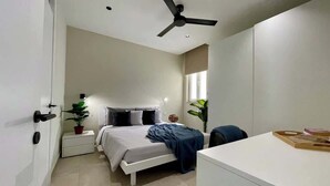 A modern bedroom with a bed, bedside tables, a desk, and a ceiling fan. - FL10 2BR Bugibba Seafront LUX Apartment (Saint Paul's Bay)