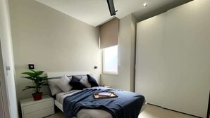 A modern bedroom with a bed, bedside table, and a potted plant.
