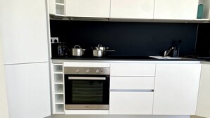 A modern kitchen with white cabinets, a built-in oven, and a black countertop.