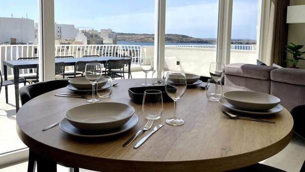 A dining table set for four with a view of the sea and buildings in the background.