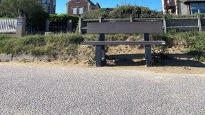 A gravel path with a bench in the foreground, leading to a traditional building with a tower and a gate. - 100m from the beach! (Hermanville-sur-Mer)