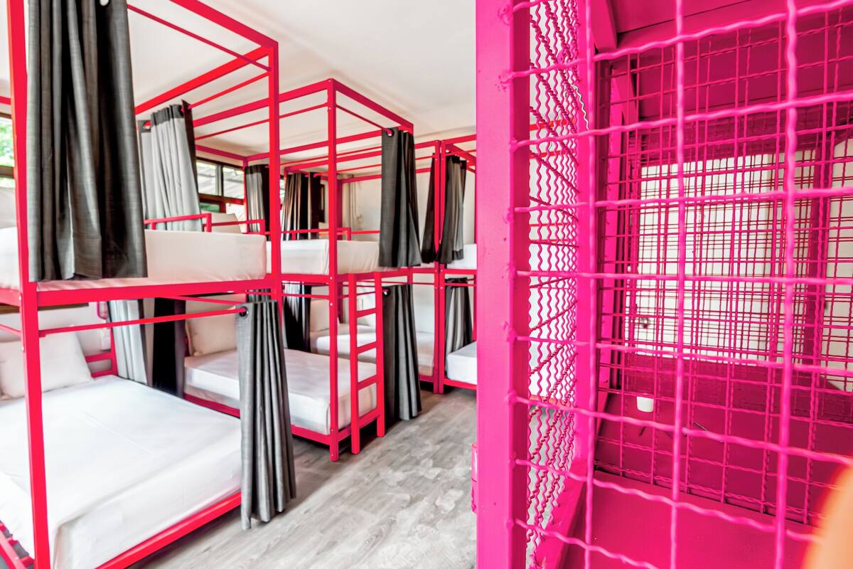 Une chambre avec des lits superposés et un paravent rose.