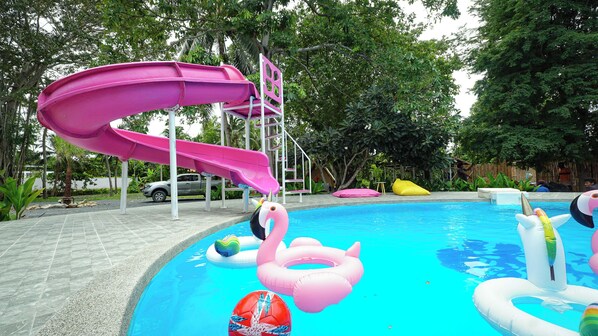 A swimming pool with a pink slide, inflatable rings, and a volleyball. - Slumber Party Koh Phangan Beach (Ko Pha-ngan)