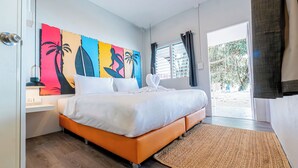 A bedroom with a bed, a nightstand, a wall art piece, a window with curtains, and a view of the outside. - Slumber Party Koh Phangan Beach (Ko Pha-ngan)