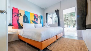 Une chambre à coucher comprenant un lit, une table de chevet, une œuvre d’art murale, une fenêtre avec des rideaux et une vue sur l’extérieur.