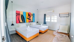 Habitación de hotel con dos camas, una obra de arte de temática playera, una ventana con cortinas y un equipo de aire acondicionado.