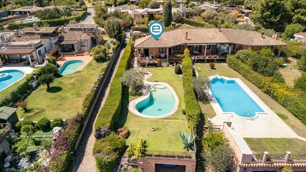 A residential property with a swimming pool, a covered patio, and a well-maintained garden.