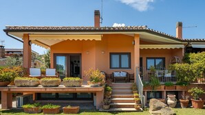A house with a tiled roof, a covered porch, and a small garden with potted plants.
