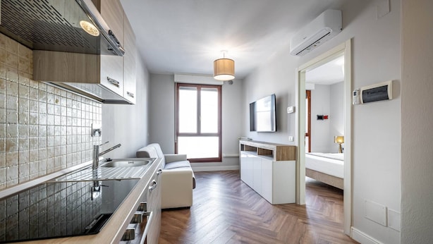 Eine moderne Küche mit Fischgrätparkett, einem eingebauten Ofen und einem großen Fenster.