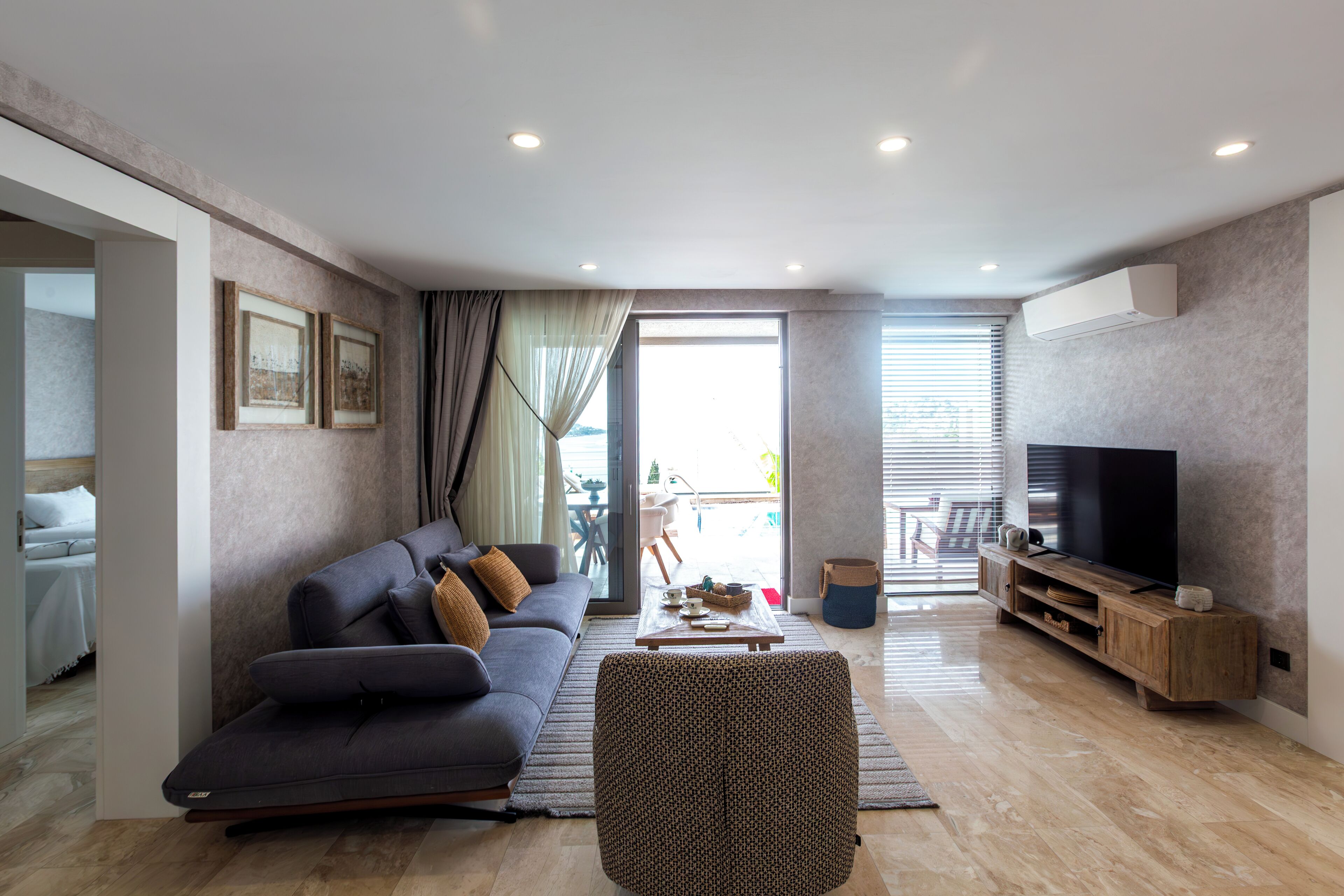 Una sala de estar moderna con un sofá, un sillón estampado, una mesa de centro y un televisor.