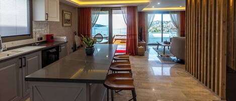 A modern kitchen with a central island, bar stools, and a view to the outside.