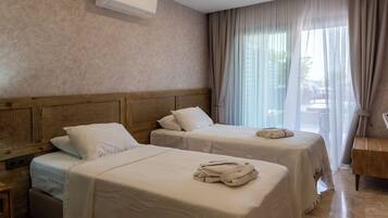Ein Hotelzimmer mit zwei Betten, einem Holzkopfstück, einem Marmorboden und einem großen Fenster mit Vorhängen.
