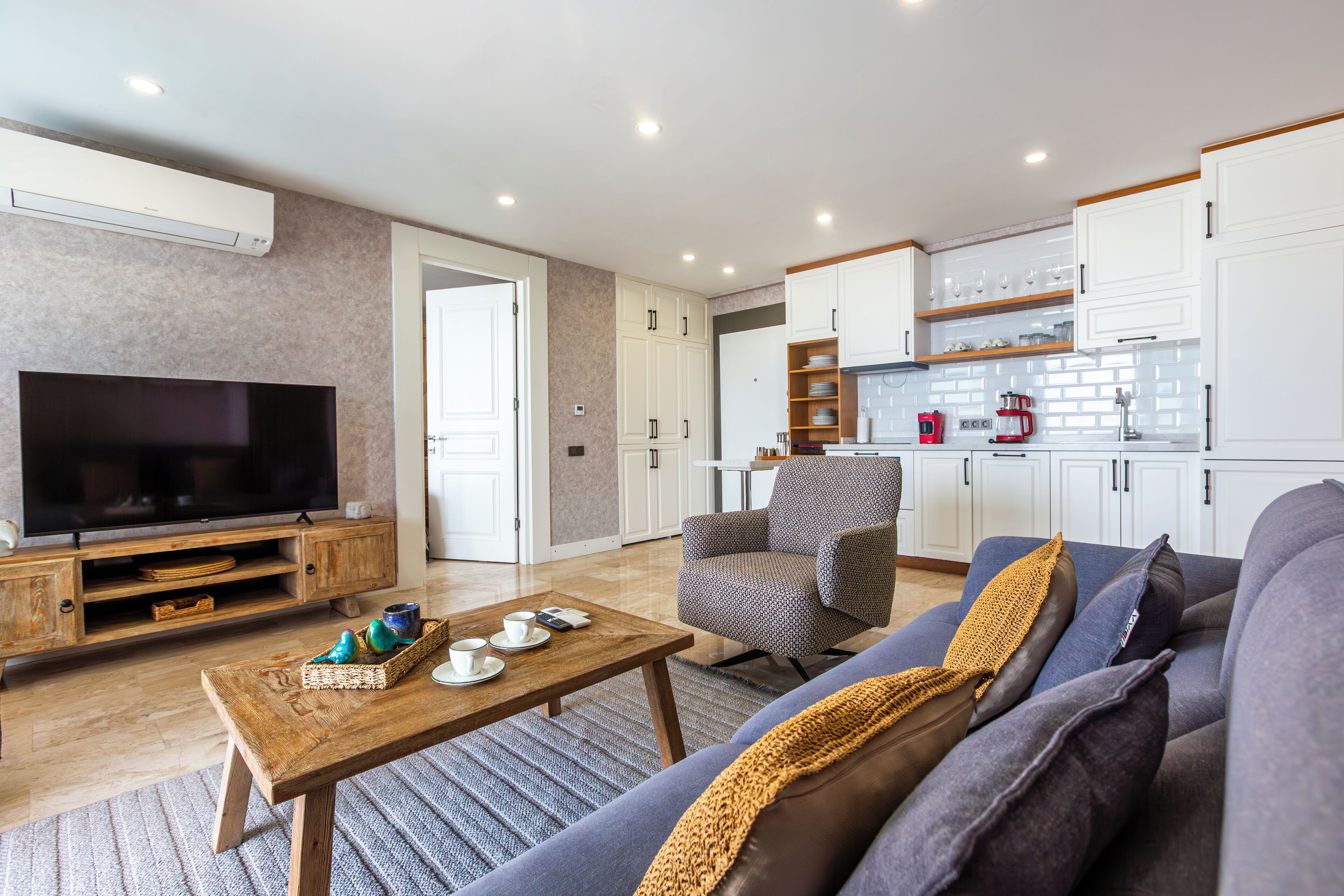 A modern living room with a flat-screen TV, wooden coffee table, and a comfortable sofa.