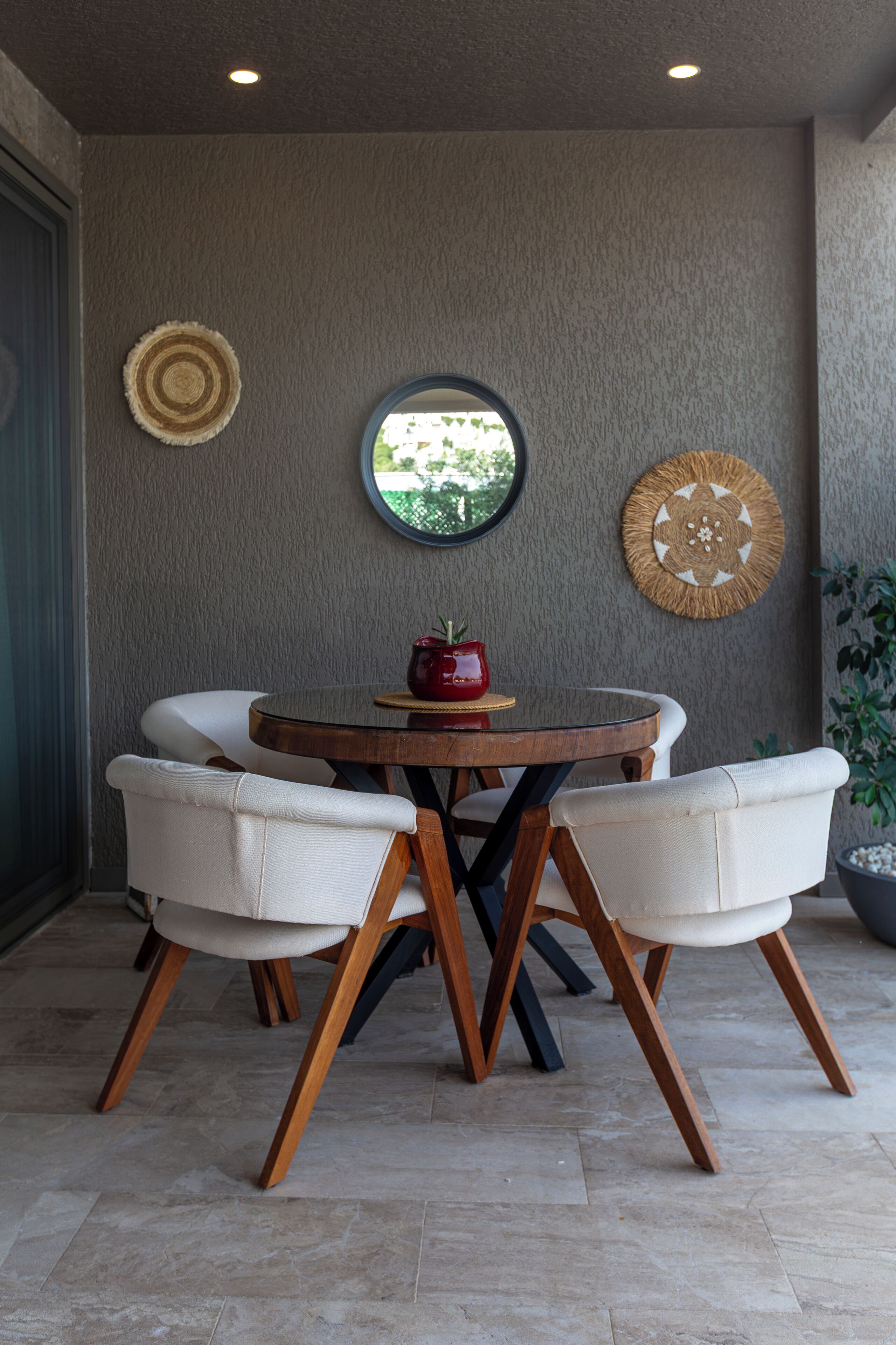 A dining area with a round table, four white chairs, and two wall decorations.