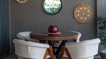 A dining area with a round table, four white chairs, and two wall decorations.