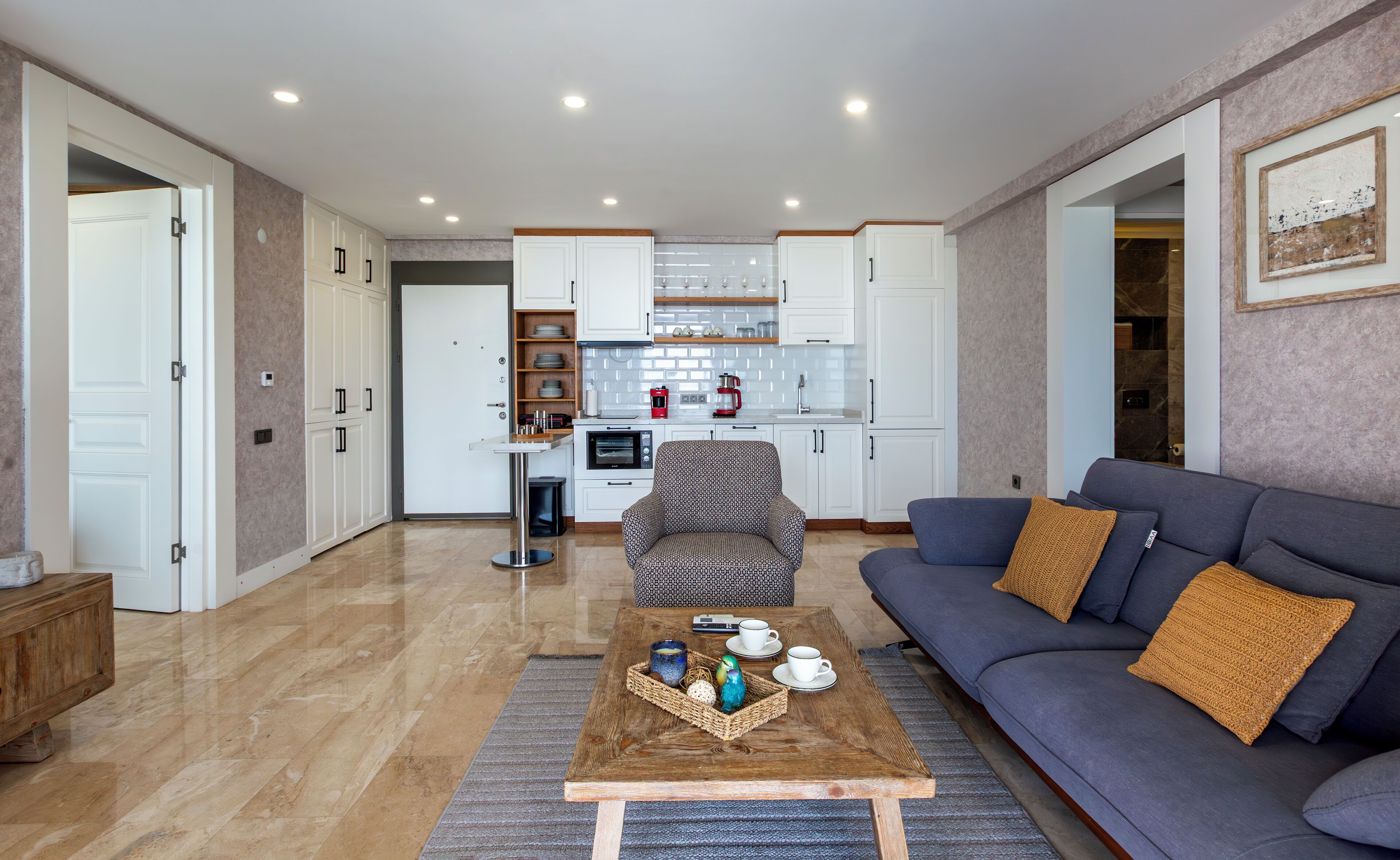 A modern living room with a sofa, coffee table, and a kitchen in the background.