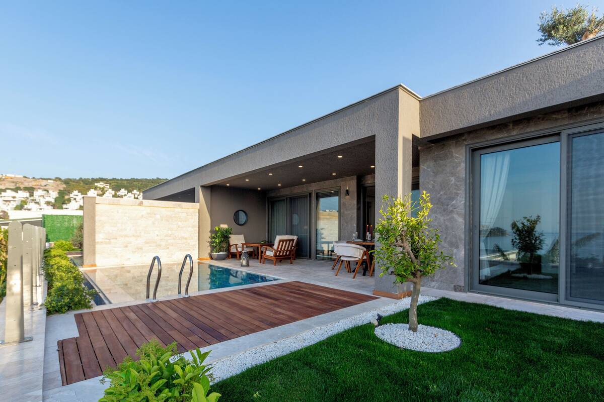A modern house with a swimming pool, outdoor seating, and a well-maintained lawn.