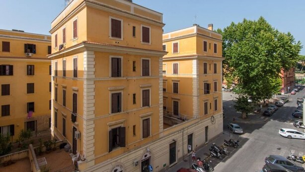A multi-story yellow building with balconies, a street view, and parked cars. - Testaccio Elegant Apartment (Rome)