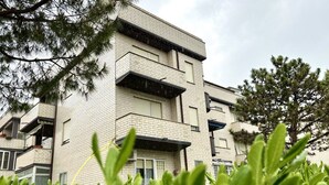 Un edificio de varios pisos con fachada de ladrillo, balcones y cielo despejado.