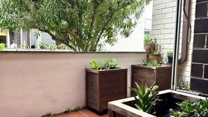Un pequeño espacio al aire libre con pared de ladrillo, plantas en macetas y un árbol.