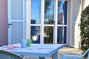 Un patio con un tavolo, due sedie e una tazza verde e bianca.