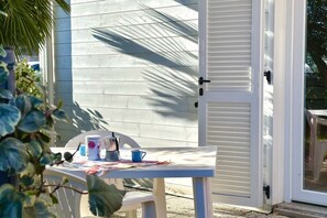 A white table with a blue mug and a white mug, a white chair, and a closed white door. - Palme 10 - Marcelli, two-room apartment with garden, Residence Le Palme (Marcelli)