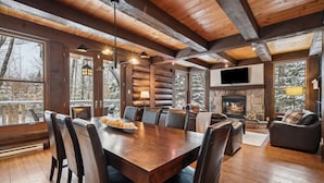 A log cabin interior with a dining area, fireplace, and large windows offering a view of snow-covered trees. - At only 7 km from Mont-Tremblant Skiing,  Dream Chalet with Spa & Fireplace (Lac superieur)