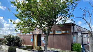Ein Gebäude mit Holzfassade, einem Schild mit der Aufschrift "CEDARS" und einem kleinen Baum davor.