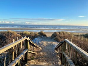 Eine Holztreppe führt zu einem Strand mit freiem Blick auf das Meer.