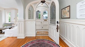 A hallway with white wainscoting, a patterned rug, and a chandelier.