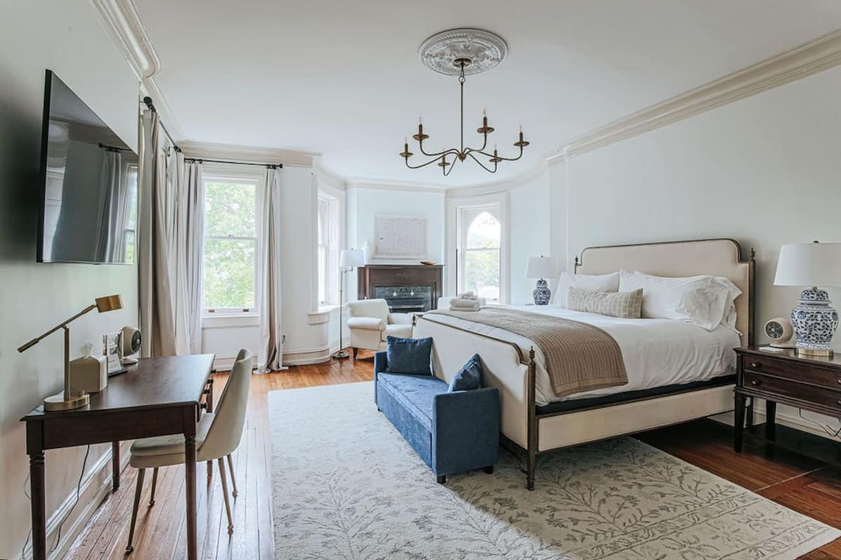 Ein Schlafzimmer mit Bett, Schreibtisch, Stuhl, Fernseher und einer Chandelier.