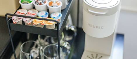 A Keurig coffee maker with a milk frother and a cup holder with various coffee pods.