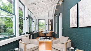 A cozy dining area with a table and chairs, large windows, and a view of greenery outside.