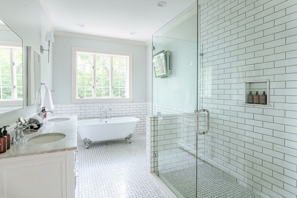 Un baño moderno con una bañera independiente, ducha con mampara de vidrio y un amplio ventanal que proporciona luz natural.